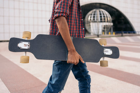 Stock photo of unrecognized skater boy walking in the city with his longboard.の写真素材