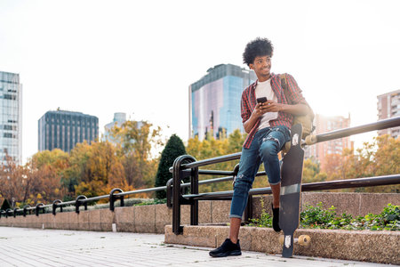 Stock photo of handsome african boy having fun in the city and using his cellphone.の写真素材
