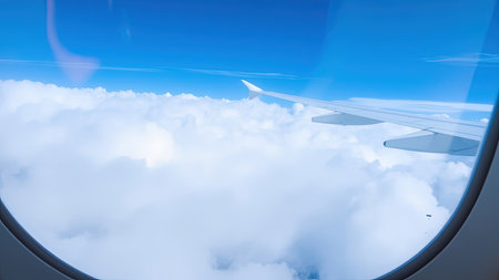 Experience the serenity of flight with this stunning aerial view showcasing a blue sky dotted with fluffy white clouds. Captured through an airplane window, the wing of the aircraft provides a unique perspective on the cloudscape below. Perfect for illustrating air travel, journeys, and vacations, this image evokes a sense of dream and serene travel. Ideal for travel agencies, blogs, or any project needing imagery of aviation, flight, or the horizon from above.の素材