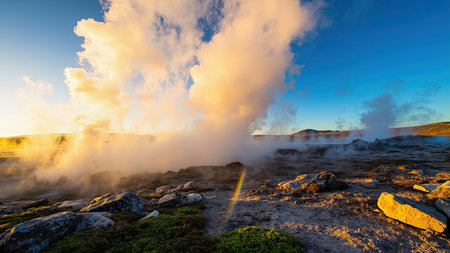 Witness the raw power of nature in this breathtaking landscape photograph of geothermal activity. Steam dramatically rises against a backdrop of a clear blue sky, showcasing the beauty of Iceland's unique geological features. Capture the essence of travel and tourism with this scenic shot of hot springs, perfect for illustrating articles on geology, environmental science, or travel brochures. The image highlights the vapor and thermal energy emanating from the earth, emphasizing the natural beauty of this extraordinary destination. This photograph will enhance any project seeking to depict the wonders...の素材