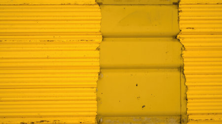 A close-up of yellow corrugated metal with horizontal lines and torn edges, creating an abstract and textured background.の素材