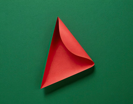 Red origami Christmas tree on green background. Minimal concept.の素材