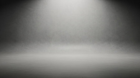 An empty photography studio background with a textured concrete surface. A soft spotlight illuminates the upper portion of the scene, creating a gradient from bright white light to dark gray shadows on the floor and wall. The overall effect is minimal and neutral.の素材