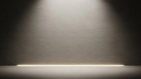 A textured wall with a rough, concrete-like surface is dramatically lit by a spotlight from above, casting shadows. A thin, warm light emanates from the floor at the base of the wall, creating a subtle glow. The overall effect is minimalist and atmospheric.の素材