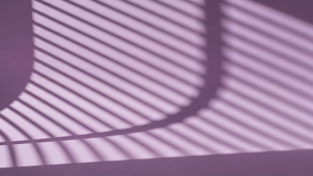 A soft purple surface is illuminated by light casting diagonal shadow lines across it, creating a striped pattern. The shadows suggest light filtering through blinds or a similar textured surface, forming a gentle, abstract background with a curved edge on the left.の素材