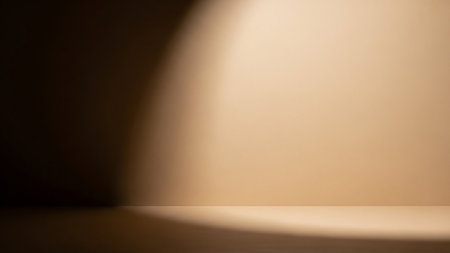 A soft, diffused light creates a warm gradient across a neutral-colored background. A distinct shadow falls on the left side, with a soft curve defining the transition between light and dark. The surface appears smooth and clean, suitable for product placement or as a subtle backdrop.の素材