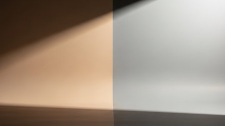 A split background image, divided vertically. The left side features a warm, soft light casting a shadow diagonally across a neutral surface. The right side displays a cooler, brighter light with a similar diagonal shadow. The overall effect is minimalist and abstract, suitable for various design applications.の素材