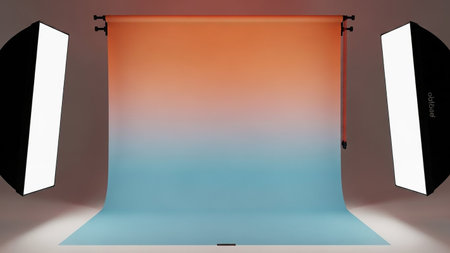 A studio setup featuring a seamless gradient backdrop transitioning from orange to blue, with two softbox lights positioned on either side.の素材