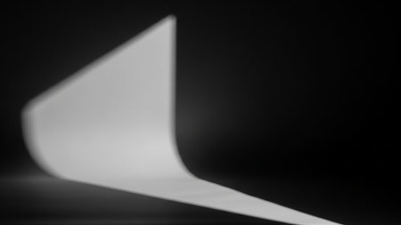 A minimalist abstract image featuring a smooth, white paper curve with soft lighting and shadows against a dark, black background.の素材