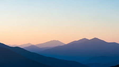 Layered mountain ranges fade into the distance under a soft gradient sky of orange, pink, and blue at sunset.の素材