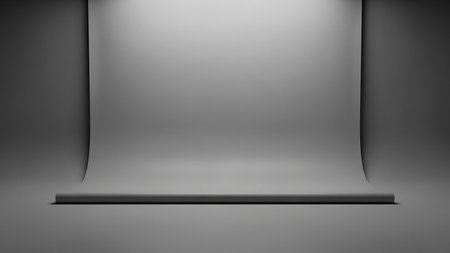An empty photography studio with a seamless grey cyclorama background and soft overhead lighting, creating a neutral and versatile space for shoots.の素材
