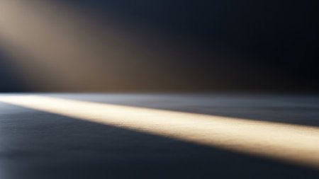 A single, bright beam of light cuts across a dark, textured surface, creating a dramatic contrast and atmospheric mood.の素材