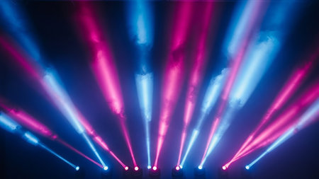 Dramatic stage lighting creates intersecting beams of vibrant pink and blue light that cut through smoky darkness, suggesting a lively performance or event.の素材