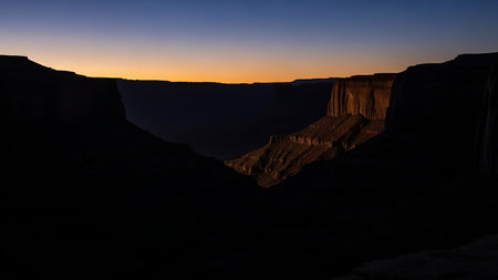 Grand showing grand canyon at dawn with sunlit layers and dark foreground. High resolution image suitable for commercial use.の素材
