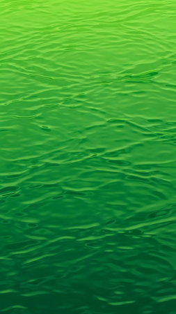 A close-up, abstract view of a vibrant green water surface with gentle ripples and subtle light reflections creating a dynamic texture.の素材