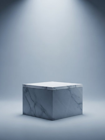 A minimalist cube pedestal made of white and grey marble is centrally placed on a light blue background, illuminated by two soft spotlights from above.の素材