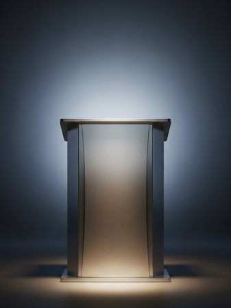 A modern, sleek metallic podium with a reflective surface stands on a stage, illuminated by dramatic lighting that casts shadows and highlights its form.の素材