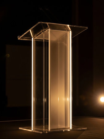 A sleek, transparent acrylic podium stands on a dark background, subtly illuminated by soft lighting, creating an elegant and modern presentation space.の素材