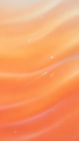 A soft, flowing gradient of orange and peach with subtle, scattered sparkles and light effects, creating a warm and gentle background.の素材