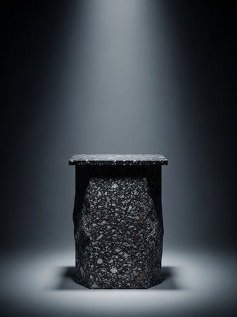 A rough-textured stone pedestal with a flat top is illuminated by a single, dramatic spotlight from above against a dark, moody background.の素材