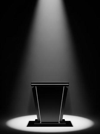 A sleek black podium stands in a dark room, dramatically illuminated by a single, focused spotlight from above.の素材