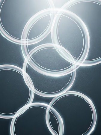 An abstract composition features several translucent, glowing rings interlocking and overlapping against a dark, subtly textured background.の素材