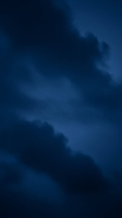 Dark blue clouds fill the frame, suggesting a stormy twilight sky. The deep indigo hues and dramatic shadows create a moody and atmospheric scene.の素材