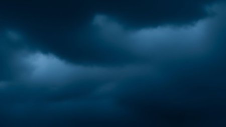 Dark blue stormy clouds fill the frame, illuminated by dramatic, moody lighting. The dense, textured clouds create an atmospheric and intense visual.の素材