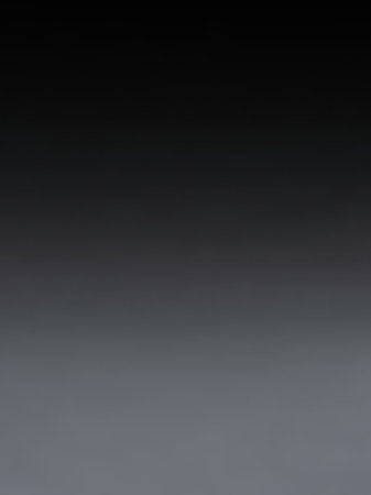 A smooth gradient from black to grey creates a minimalist abstract background with subtle tonal variation.の素材