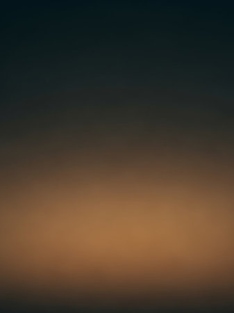 A smooth gradient transitions from a dark charcoal gray at the to a warm, muted golden brown at the bottom, creating a subtle abstract effect.の素材