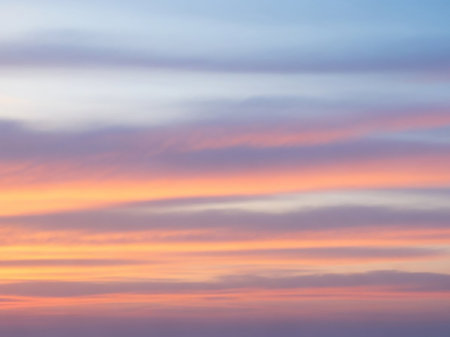 Horizontal showing a soft, horizontal gradient of pastel colors in the sky with delicate, wispy clouds transitioning from light blue to pink and orange hues.の素材