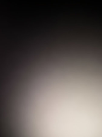 A soft, out-of-focus gradient background a warm light beige on the right fading into a muted dark gray on the left.の素材