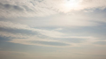 A bright, overcast sky with soft, wispy clouds and diffused sunlight creating a gentle, serene atmospheric backdrop.の素材