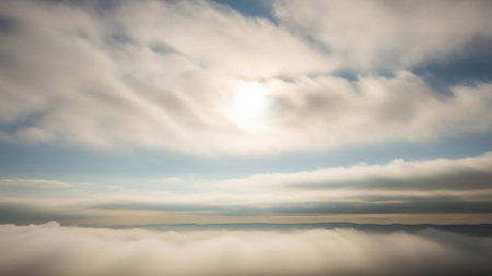 An aerial perspective a vast expanse of fluffy white clouds with the sun shining brightly. A hazy horizon is visible in the distance.の素材