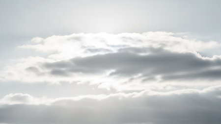 Bright sunlight filters through and illuminates a cluster of soft, textured white and gray clouds, creating a luminous and ethereal effect.の素材