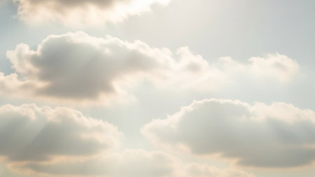 A bright sky is filled with fluffy white cumulus clouds, illuminated by soft golden sunlight casting gentle rays.の素材