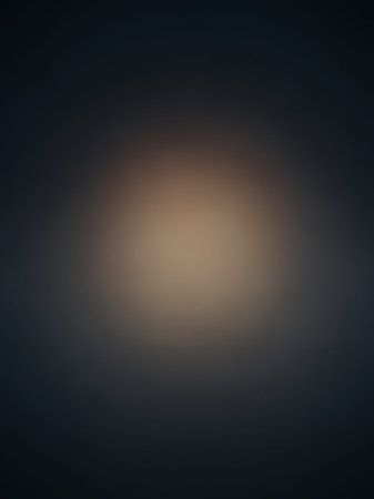 A dark gray and brown blurred background is illuminated by a soft, warm light source in the center with a subtle vignette.の素材