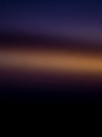 A smooth, blurred gradient transitions from deep indigo at the to a warm amber glow near the center, fading into dark black at the bottom.の素材