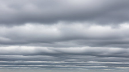 Numerous horizontal layers of flat, grey stratus clouds fill the sky, creating a uniform and overcast appearance.の素材