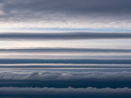 Distinct horizontal layers of clouds create a striking striped pattern against a soft blue sky in this atmospheric view.の素材