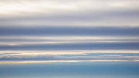 Horizontal bands of pale blue and grey clouds form a striped pattern across the sky, creating a subtle, serene backdrop.の素材