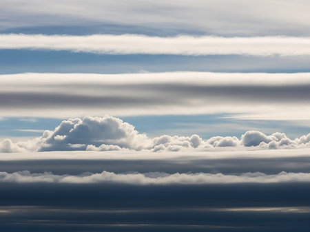 Layered stratocumulus clouds in a blue sky, forming distinct horizontal bands of white and gray, creating a sense of atmospheric depth.の素材