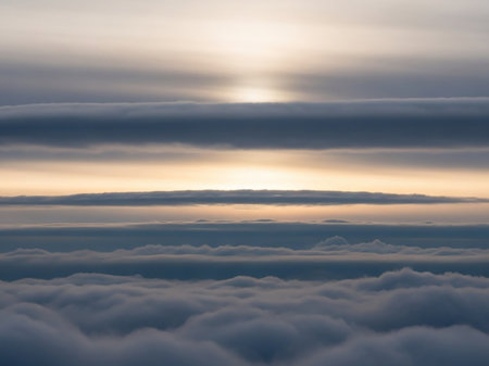 Horizontal layers of dark grey and white clouds dominate the sky, with a bright band of sunlight illuminating the horizon.の素材