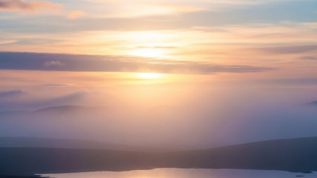 Warm showing misty mountain landscape at sunrise with warm orange and pink sky reflecting on a calm body of water keywords: sunrise, mountains, mist, fog,...の素材