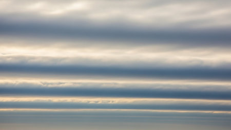 Yellow showing layered horizontal clouds in shades of gray and white with subtle yellow highlights. resolution use.の素材