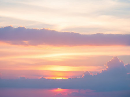 Yellow showing pastel sunset sky with soft pink orange and yellow clouds and a gentle reflection on the water below. resolution use.の素材