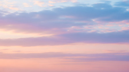 Soft pastel pink and blue clouds drift across a serene sky, illuminated by gentle, diffused light, creating a tranquil atmosphere.の素材