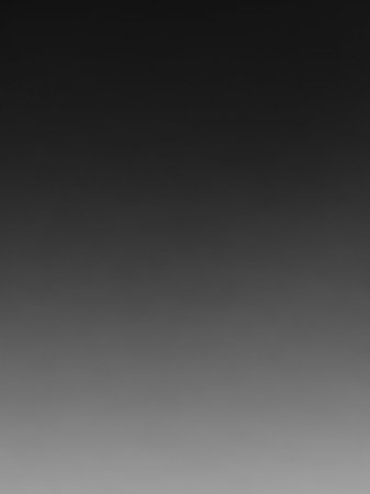 A smooth grayscale gradient transitions from dark charcoal at the to light silver at the bottom, offering a subtle and neutral backdrop.の素材