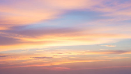 A serene sky filled with soft, wispy clouds painted in delicate pastel shades of pink, orange, yellow, and light blue during a sunset or sunrise.の素材