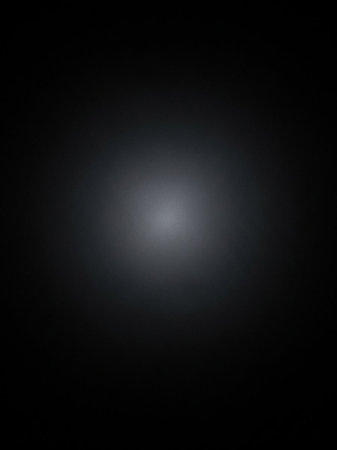 A soft, diffused white light spot is centered on a dark, subtly textured background with a gentle gradient.の素材